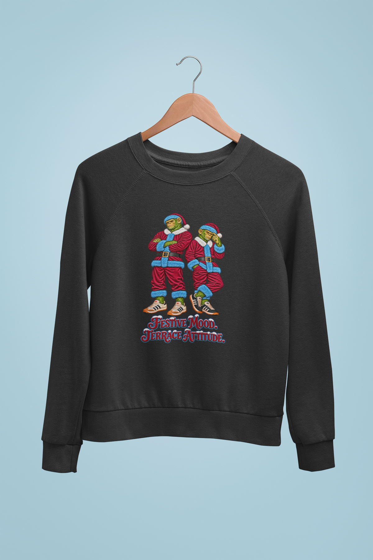Claret and blue Santa chimps Christmas sweatshirt on a hanger against a blue wall