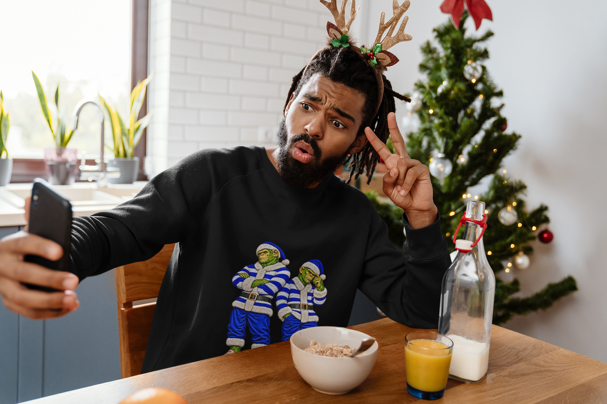 Man taking a selfie at a breakfast table wearing the blue and white hoops Santa chimps sweatshirt