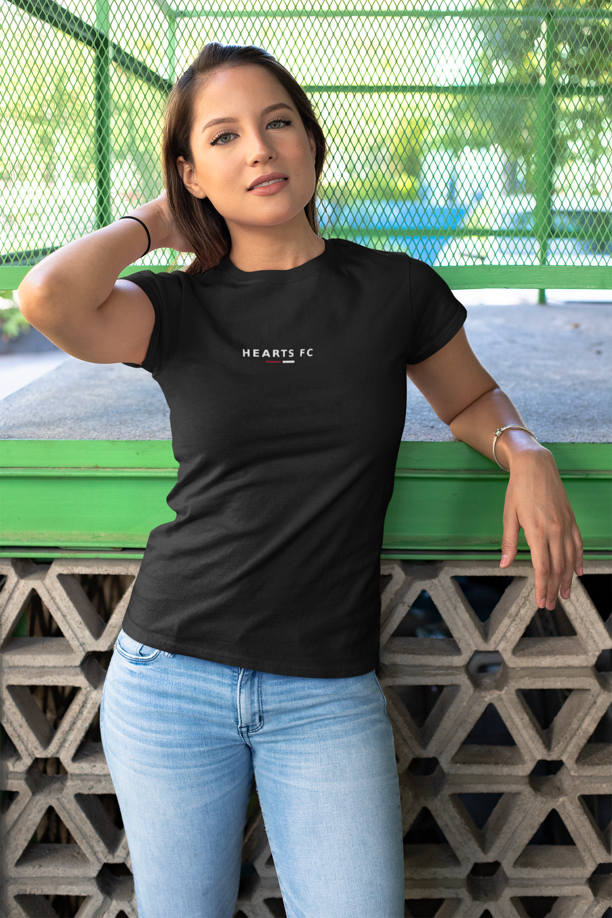 Woman leaning on a wall wearing the black Hearts FC T-shirt