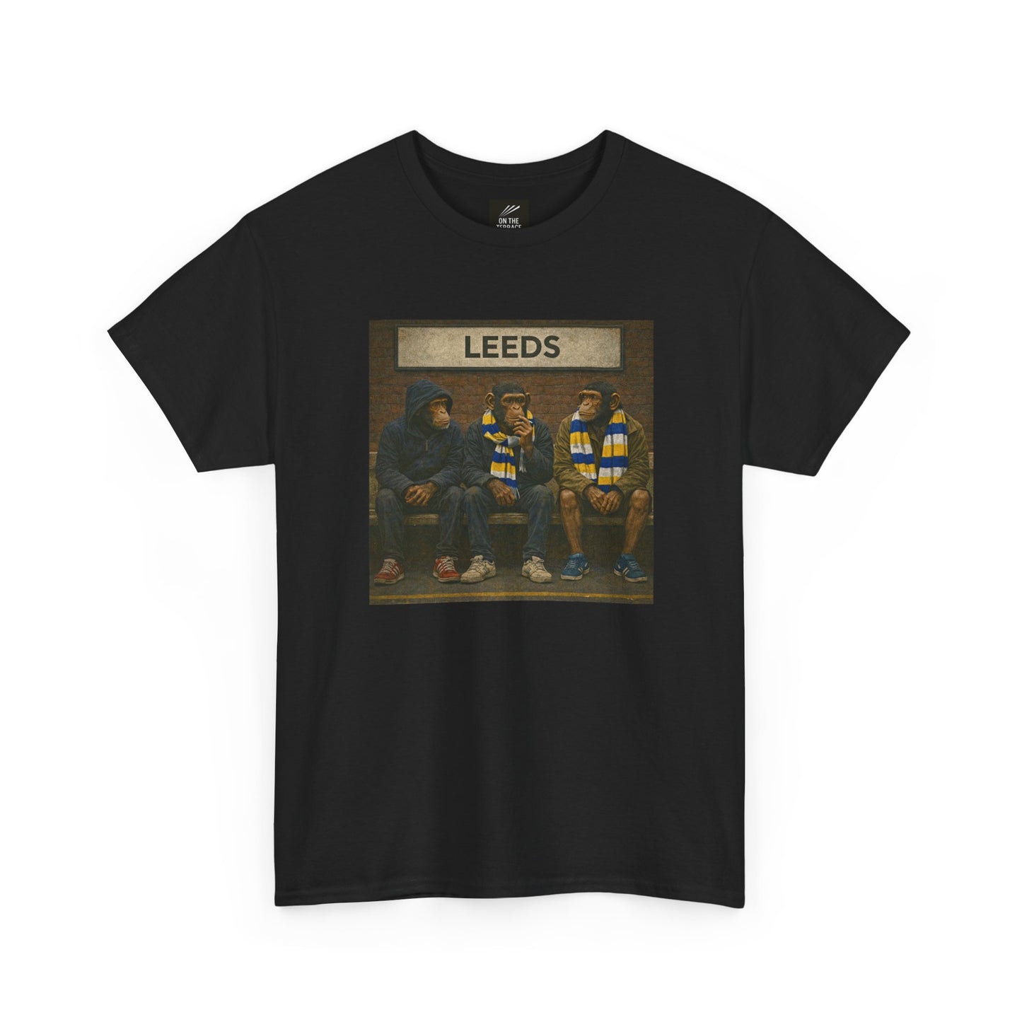 A black short-sleeve crewneck Leeds t-shirt featuring a rectangular graphic print on the chest. The graphic shows three hooded figures sitting on a bench, with a banner above them reading 'LEEDS'.