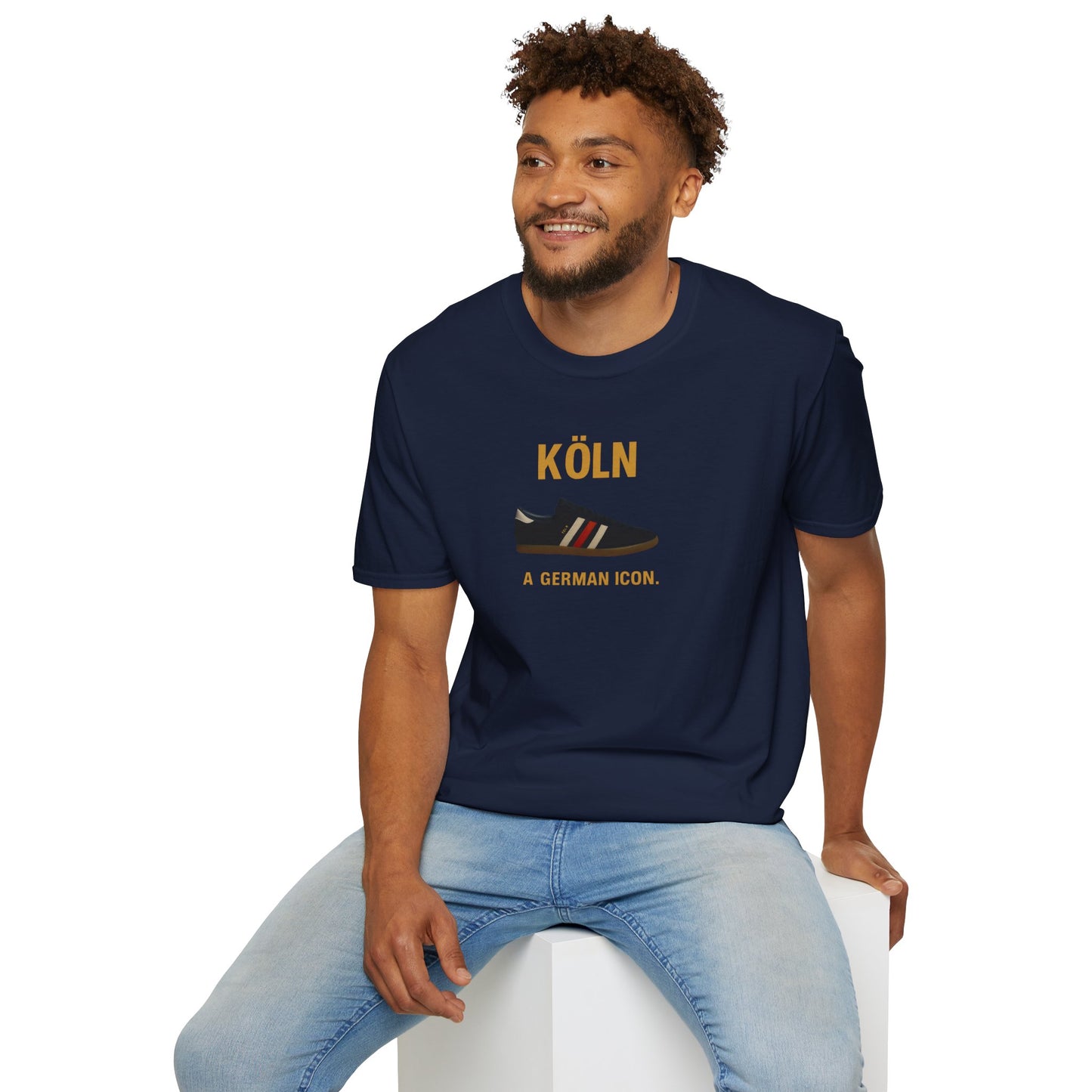 Smiling man wearing navy blue Köln t-shirt with a German sneaker graphic and light blue jeans