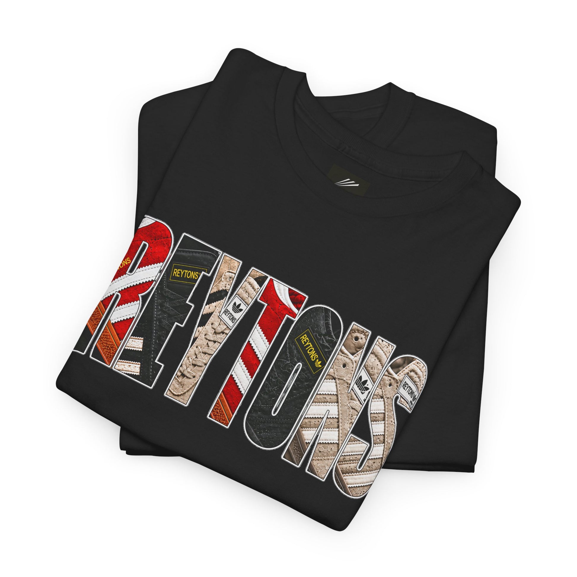 A folded black Reytons t-shirt with a large graphic print reading 'Reytons' in a distressed, multi-patterned font featuring red, white, black, and beige designs, on a plain white background.