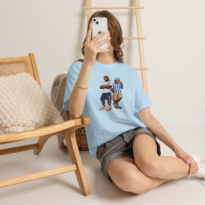 Woman in a chair taking a selfie in the sky blue Coventry Monkeys Duo tee