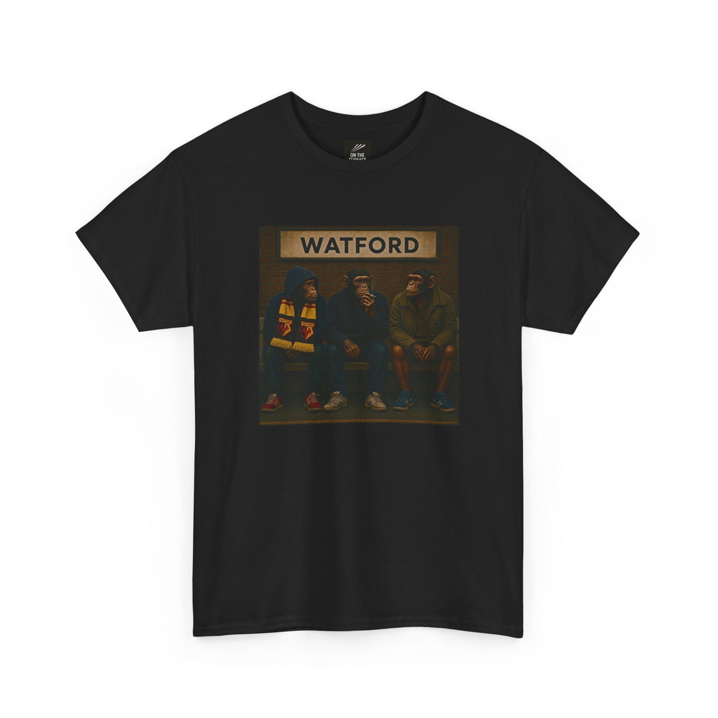 A black short-sleeve Watford t-shirt featuring a rectangular graphic print on the chest. The graphic shows three hooded figures sitting on a bench under a sign that reads 'WATFORD' in beige letters, with a dark background.