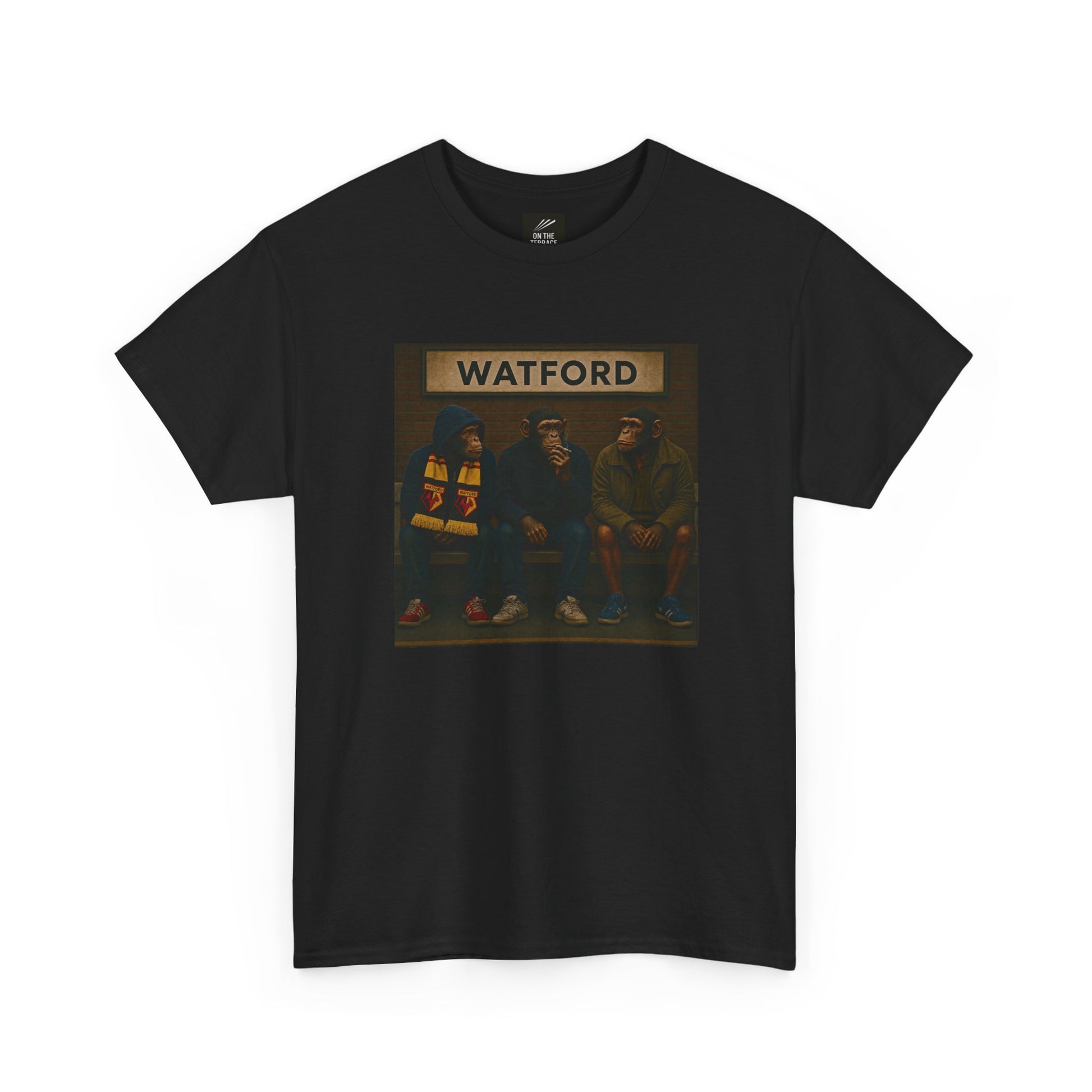 A black short-sleeve Watford t-shirt featuring a rectangular graphic print on the chest. The graphic shows three hooded figures sitting on a bench under a sign that reads 'WATFORD' in beige letters, with a dark background.