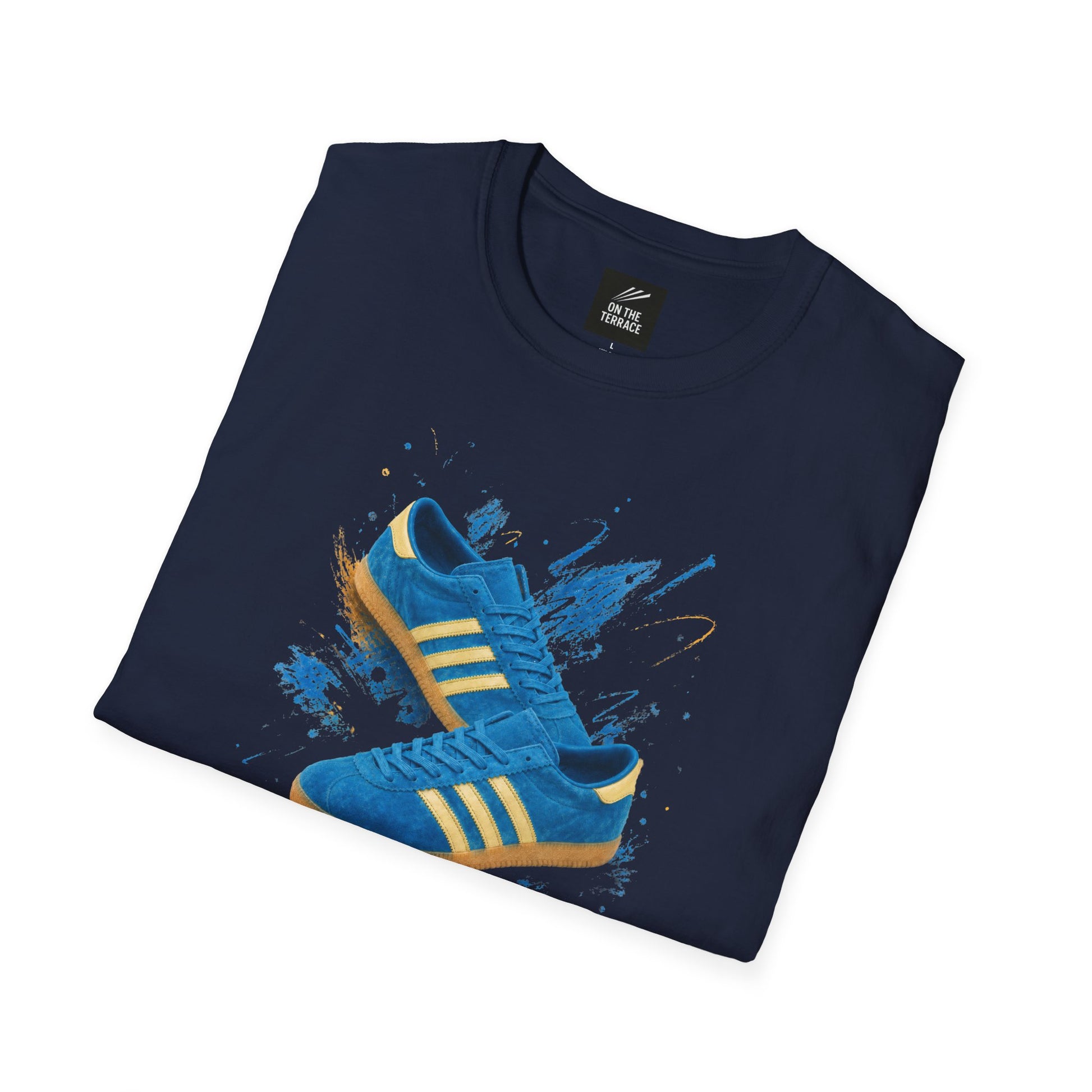Navy blue t-shirt with a printed graphic of a blue suede trainer featuring cream stripes and a gum sole, surrounded by a blue and gold paint splatter design, with an "On The Terrace" logo on the neck label.