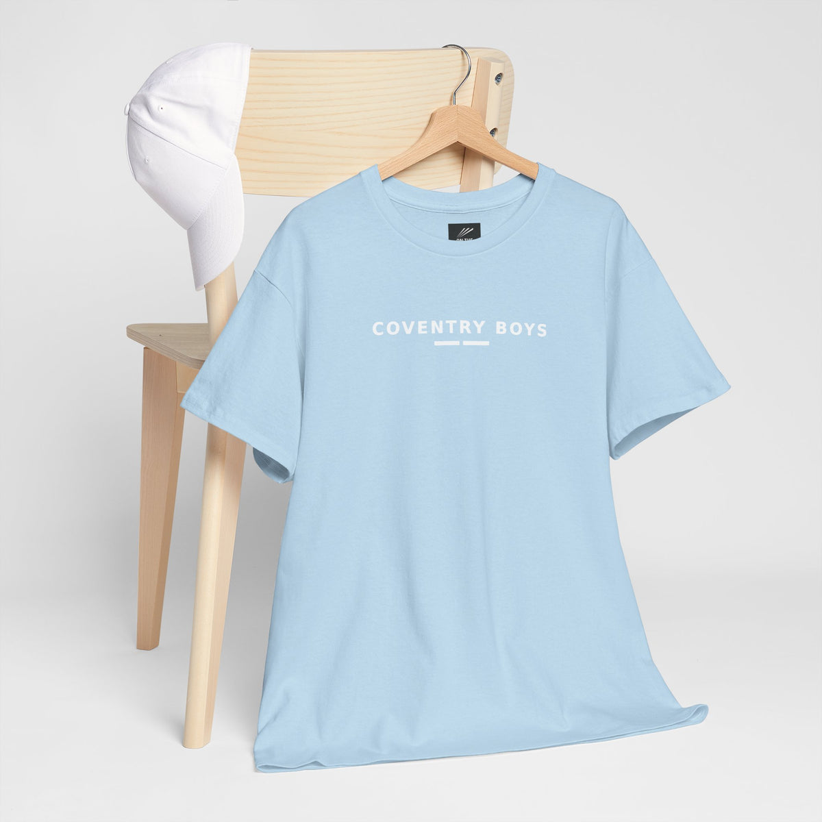 Sky blue Coventry Boys T-shirt on a hanger by a chair