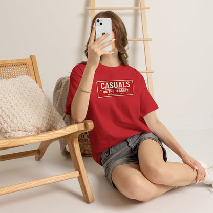 Person wearing a red Rotherham t-shirt with the number 19, sitting on the floor with a wooden chair and ladder in the background.