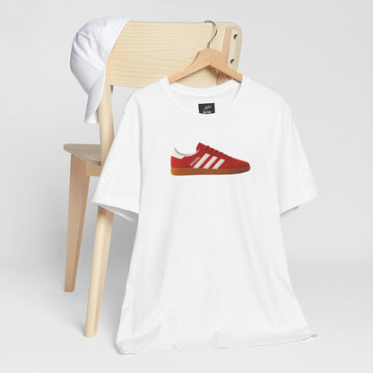 White t-shirt with red sneaker graphic and white cap on wooden chair on white background