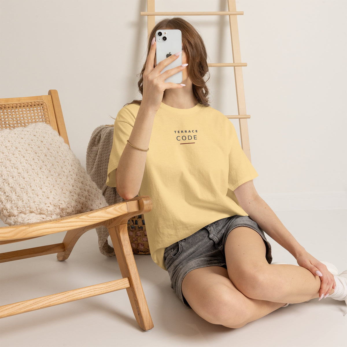 Woman sitting in a chair wearing the pale yellow Terrace Code T-shirt