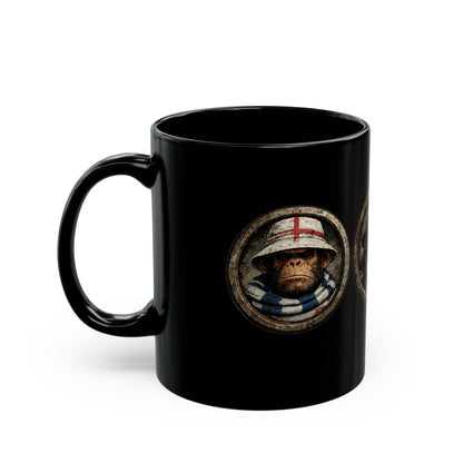 A black ceramic mug features three circular, stone-textured portrait emblems. The central emblem showcases a chimpanzee with a stern expression, wearing a navy blue casual jacket and a navy bucket hat with red and white stripes. The left emblem shows a monkey wearing an England St. George's cross bucket hat and a blue-and-white bar scarf. The right emblem shows a monkey in a red casual cap and scarf.