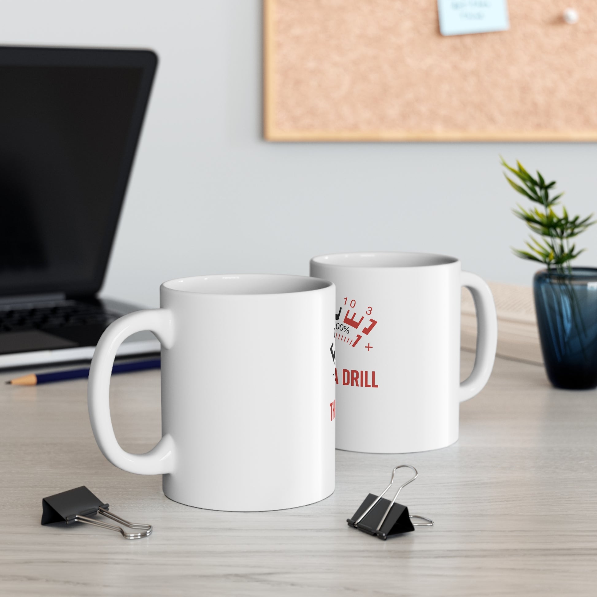 Two white ceramic mugs on a light wood desk with a laptop, pencils, binder clips, corkboard, and small plant