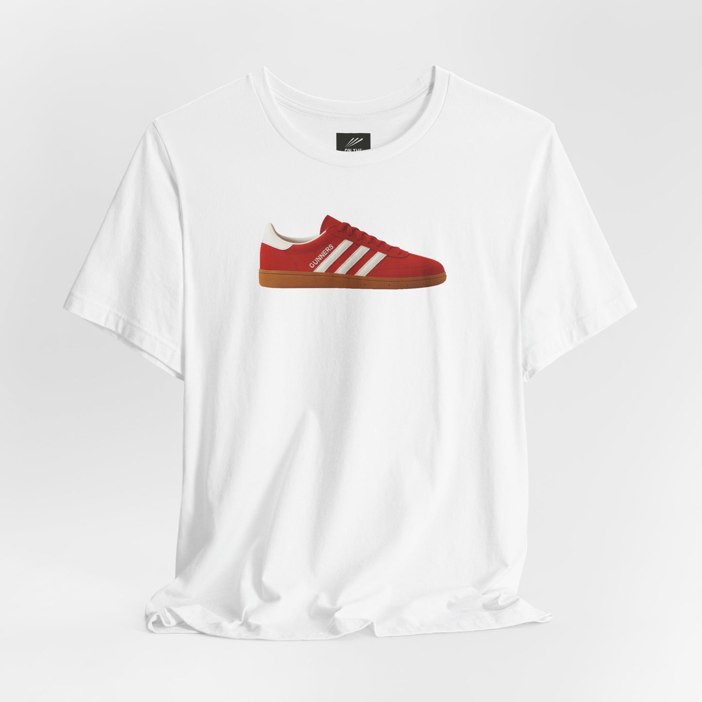 White t-shirt featuring a red sneaker graphic with white stripes and gum sole, labeled Gunners