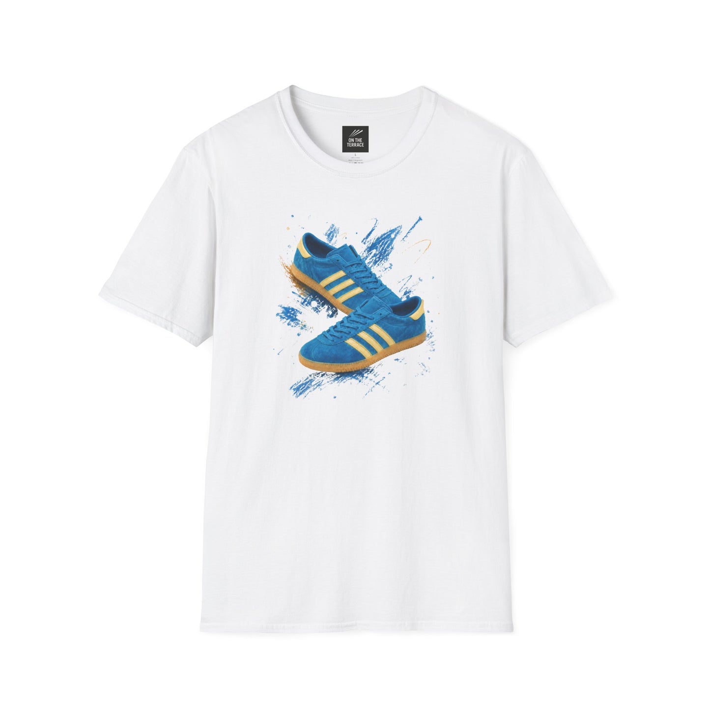 White t-shirt with a graphic print of a blue suede trainer with cream three stripes and gum sole, set against a blue and gold paint-splash background, On The Terrace neck label visible.