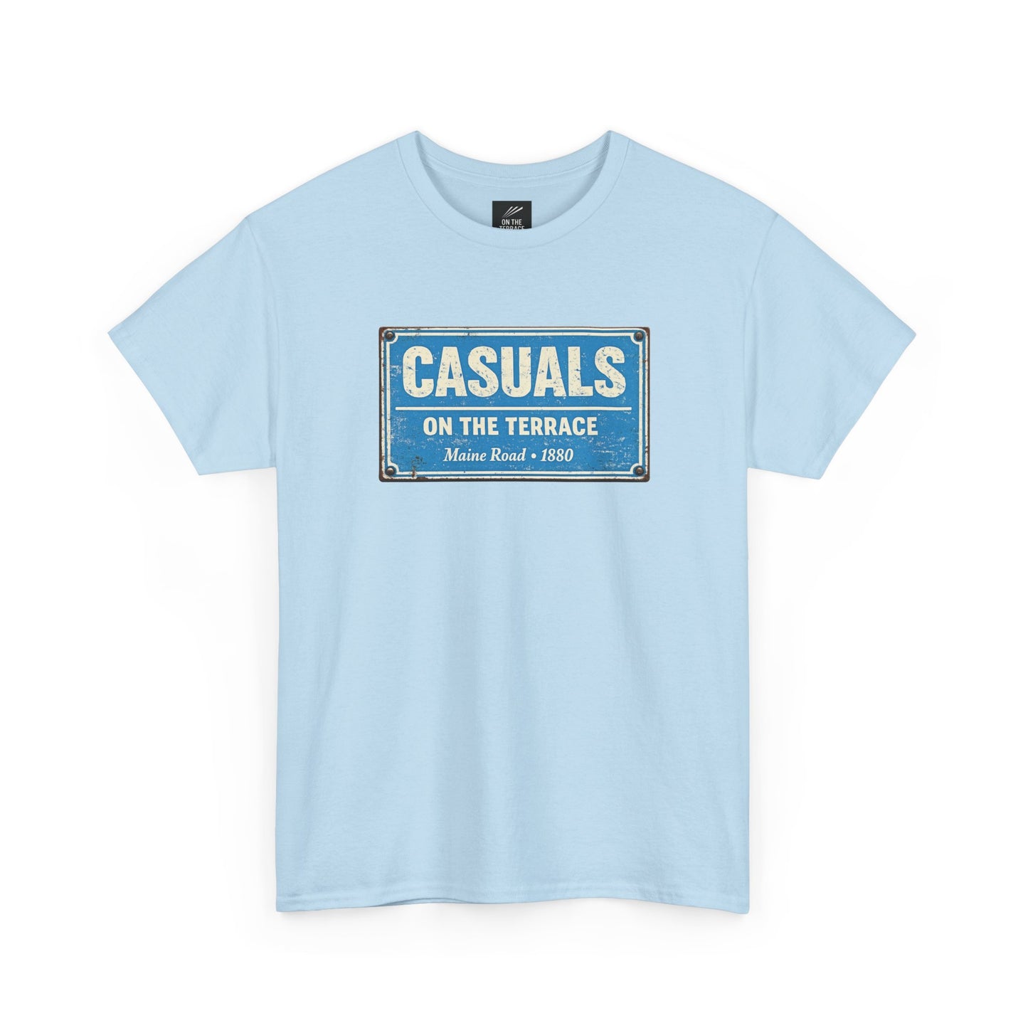A sky blue MCFC t-shirt featuring a central vintage blue and white street sign graphic reading "CASUALS ON THE TERRACE" with "Maine Road • 1880" printed below, and an inner neck label for On The Terrace.