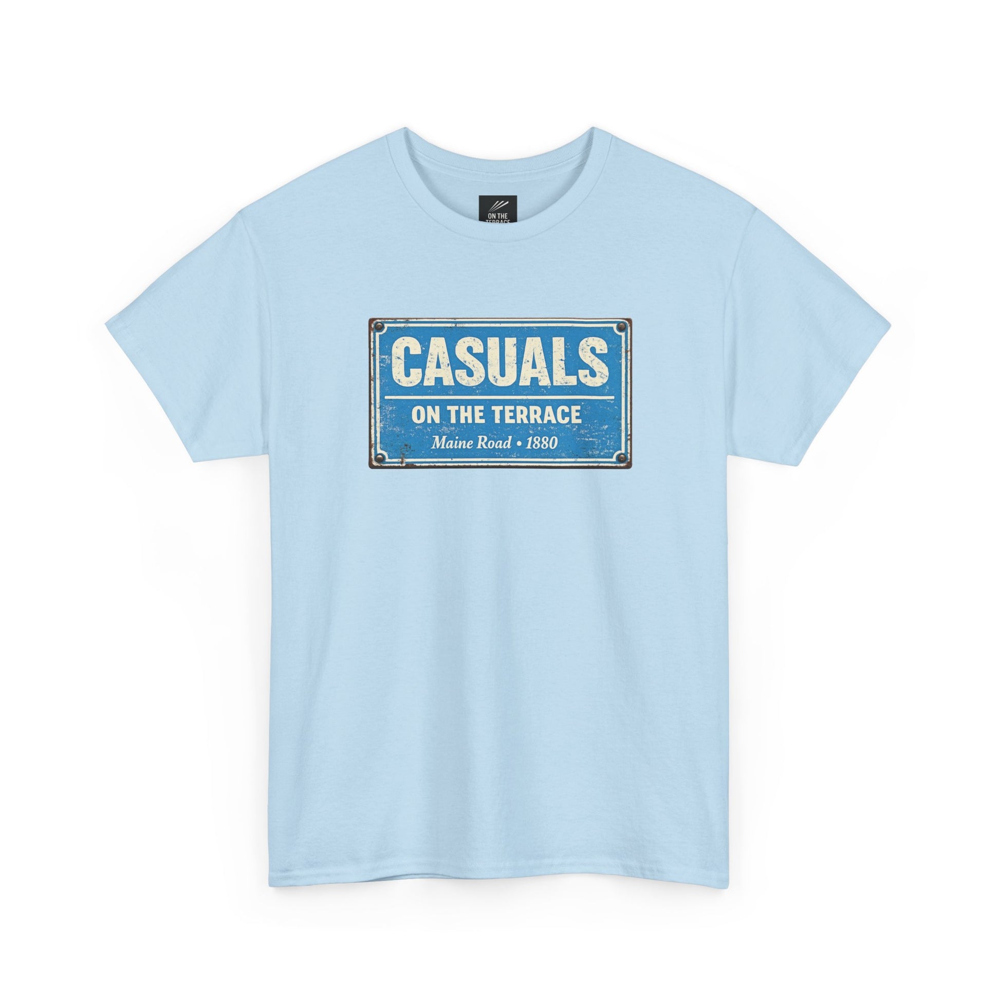 A sky blue MCFC t-shirt featuring a central vintage blue and white street sign graphic reading "CASUALS ON THE TERRACE" with "Maine Road • 1880" printed below, and an inner neck label for On The Terrace.