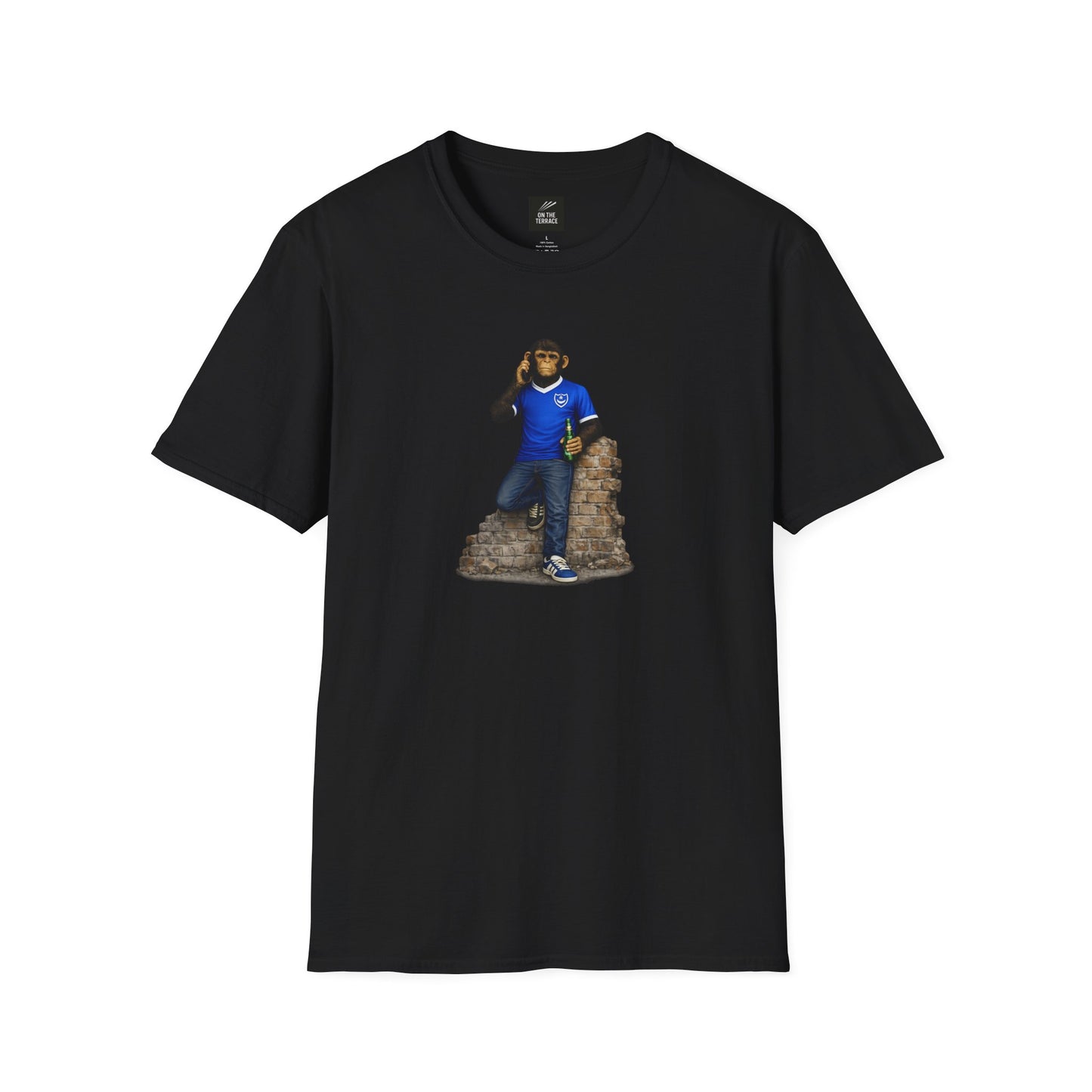 A black short-sleeved crew-neck t-shirt featuring a central graphic of a chimpanzee dressed in a solid blue football jersey, denim jeans, and blue trainers. The character is leaning against a section of a ruined brick wall while holding a green bottle and talking on a mobile phone.