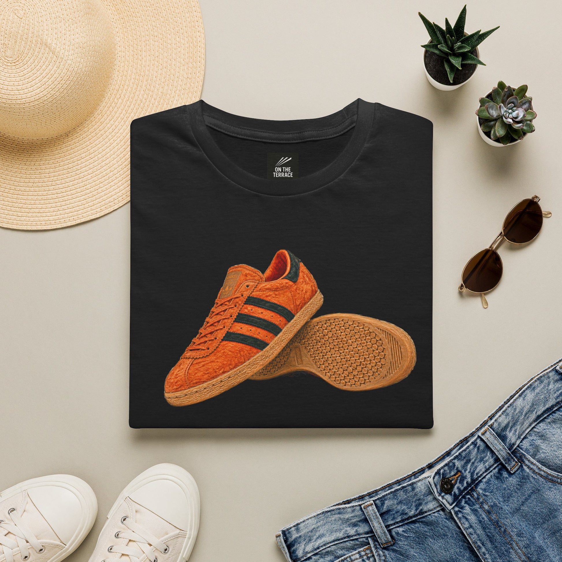 Black t-shirt with orange retro sneaker graphic print showing side and sole view