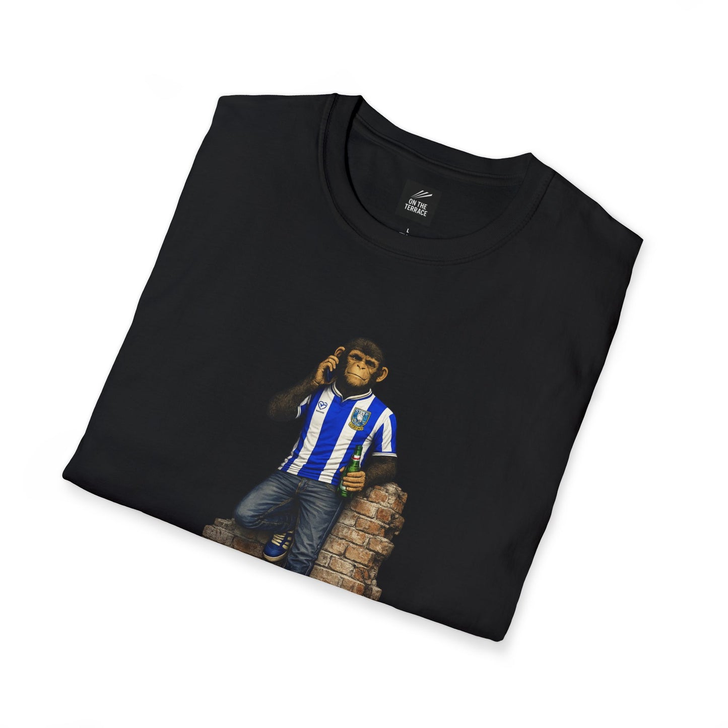 A folded black t-shirt showcasing the Sheffield Wednesday-themed "Northern Monkey" graphic, highlighting the blue and white striped jersey and the "On The Terrace" internal branding