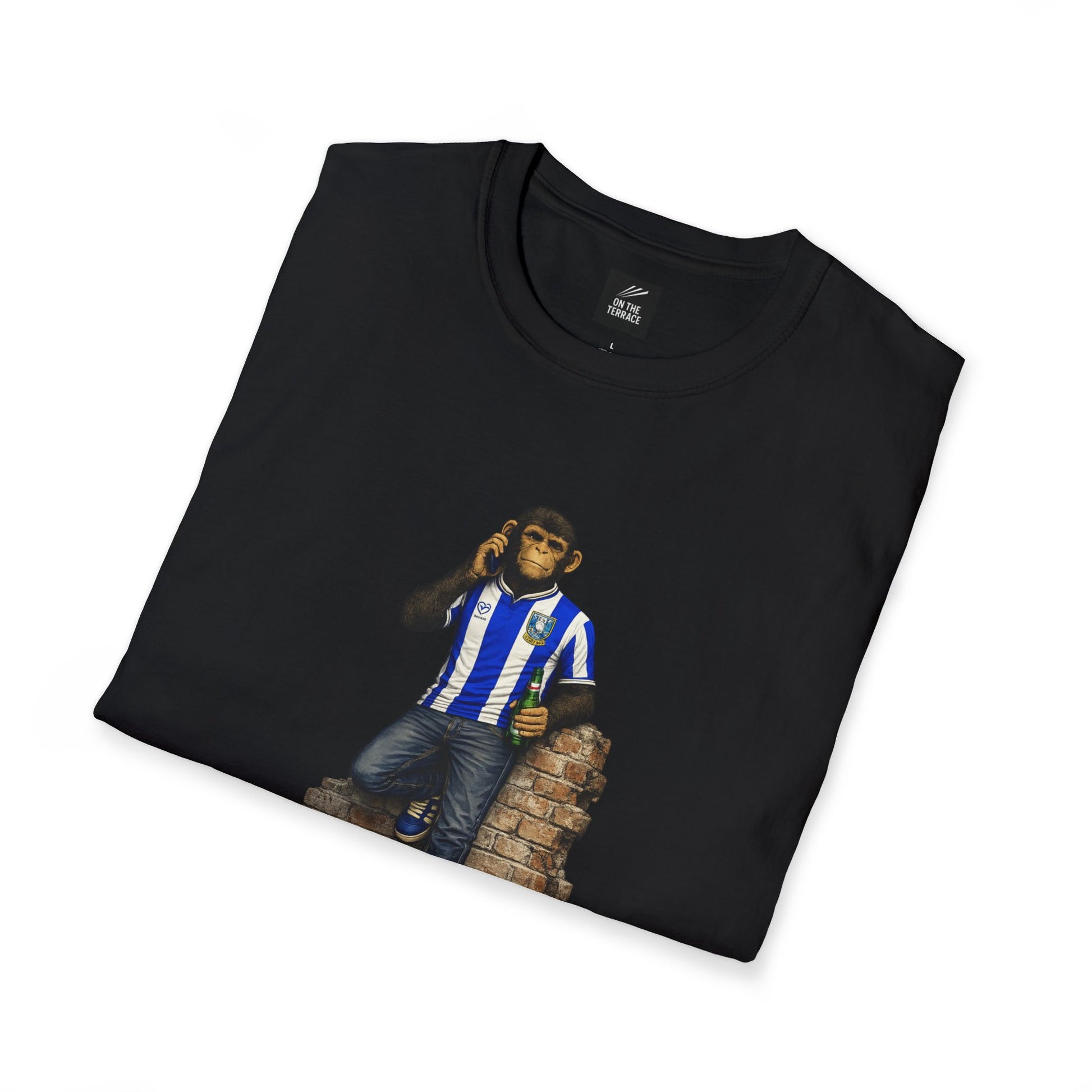 A folded black t-shirt showcasing the Sheffield Wednesday-themed "Northern Monkey" graphic, highlighting the blue and white striped jersey and the "On The Terrace" internal branding
