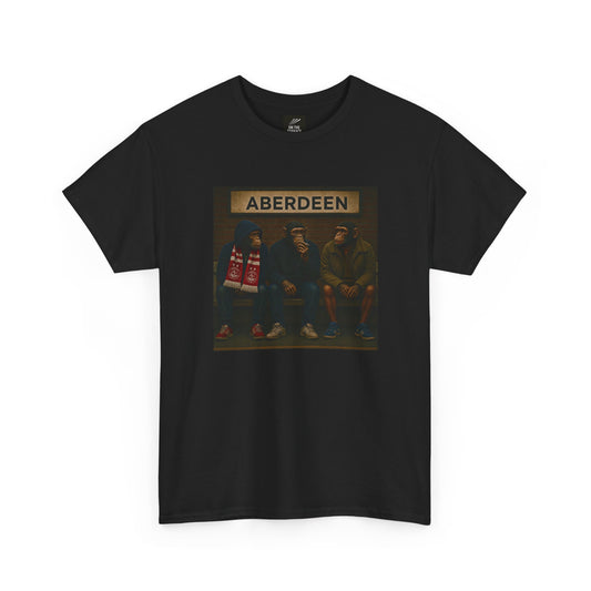 A black short-sleeve crewneck Aberdeen t-shirt featuring a rectangular graphic print on the chest. The graphic shows three men sitting on a bench under a sign that reads 'ABERDEEN', with one man holding a red and white striped scarf.