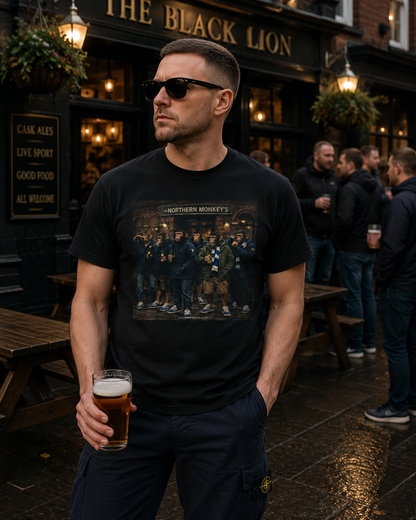 A man wearing a black graphic t-shirt with a band print and sunglasses, holding a pint of beer outside The Black Lion pub.
