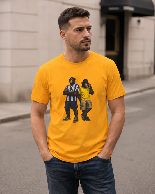 A man wearing a bright yellow swfc t-shirt with a graphic print of two men, standing on a city street.