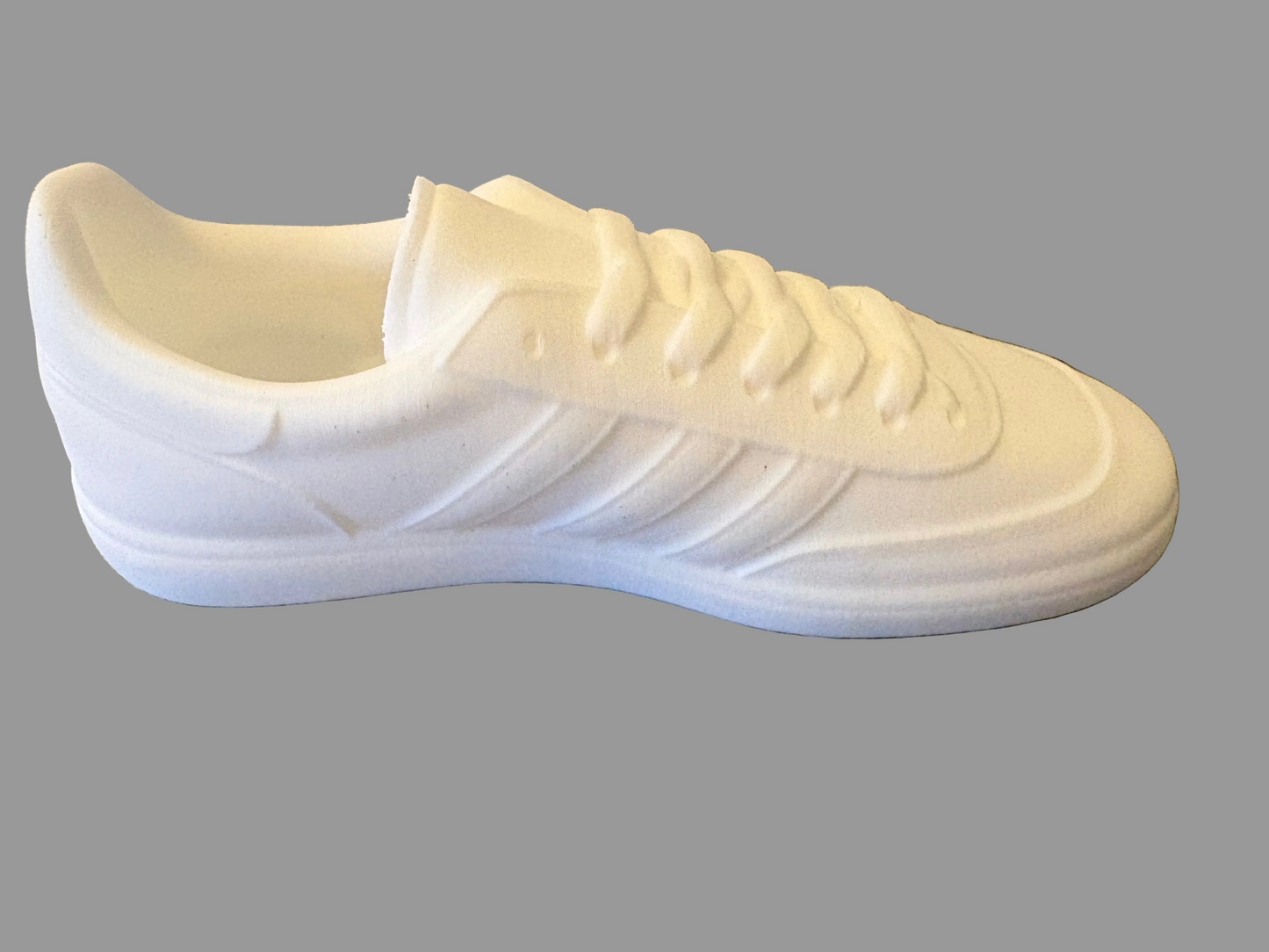 White adidas manchester sneaker on a textured gray surface