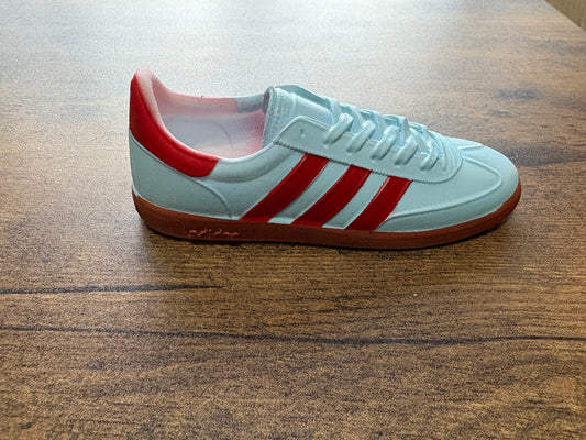 White sneaker with red stripes on a wooden surface