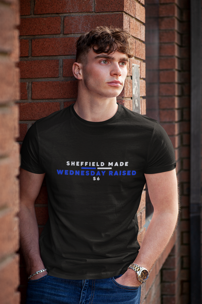 Young man leaning on a brick wall in black Sheffield Made Wednesday Raised tee