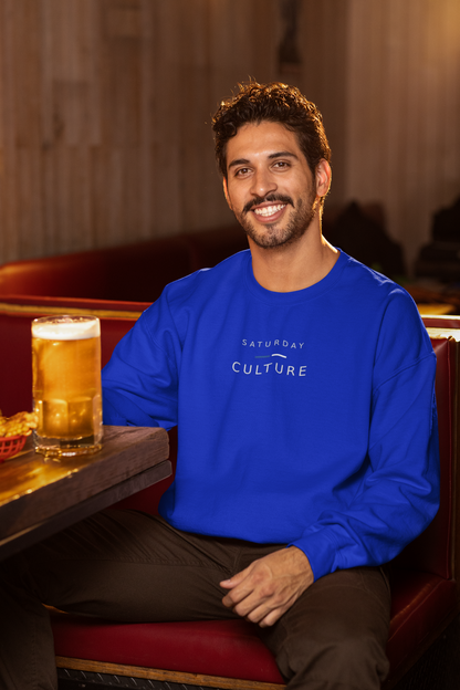 Man in a pub with a pint wearing the royal blue Saturday Culture football casuals sweatshirt