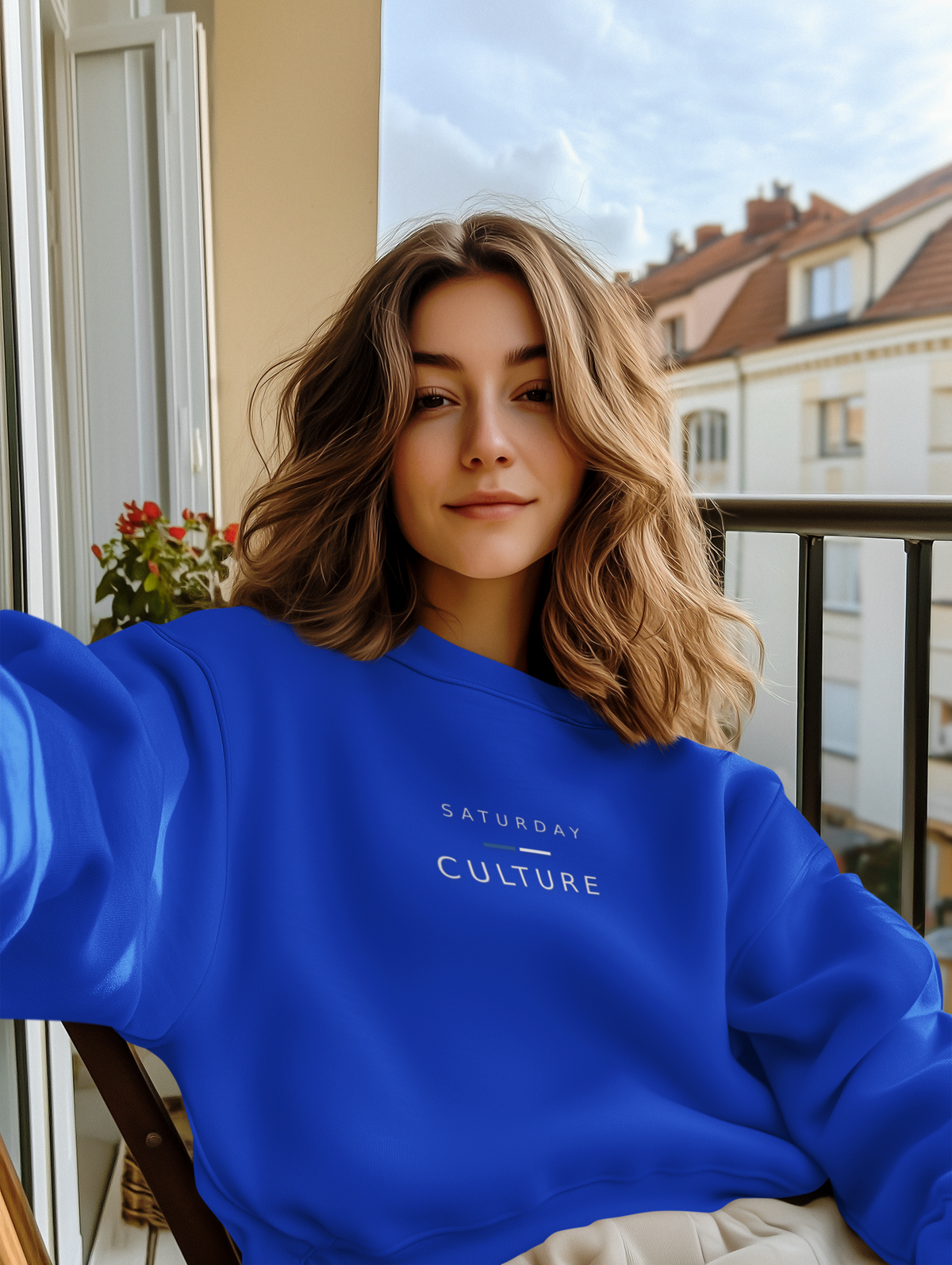 Woman on a balcony wearing the royal blue Saturday Culture sweatshirt