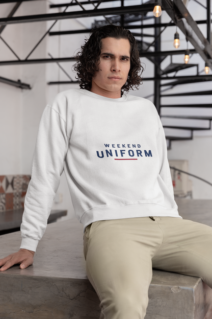 Man sitting on concrete steps wearing the white Weekend Uniform sweatshirt and beige trousers