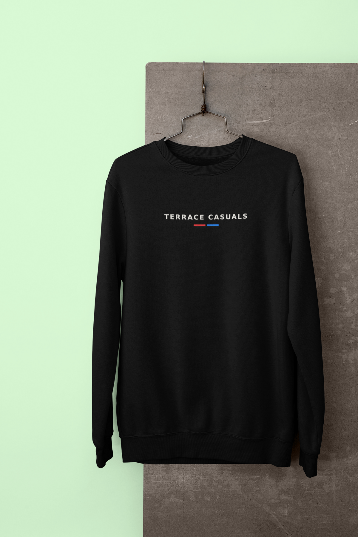 Black Terrace Casuals embroidered sweatshirt hanging against a pale green wall