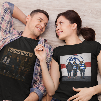 A man and a woman lying side by side on a light wood floor, wearing black graphic swfc t-shirts. The man's shirt features a 'WEDNESDAY' graphic with a police box, and the woman's shirt features a graphic of the band Wednesday with the CBC logo.