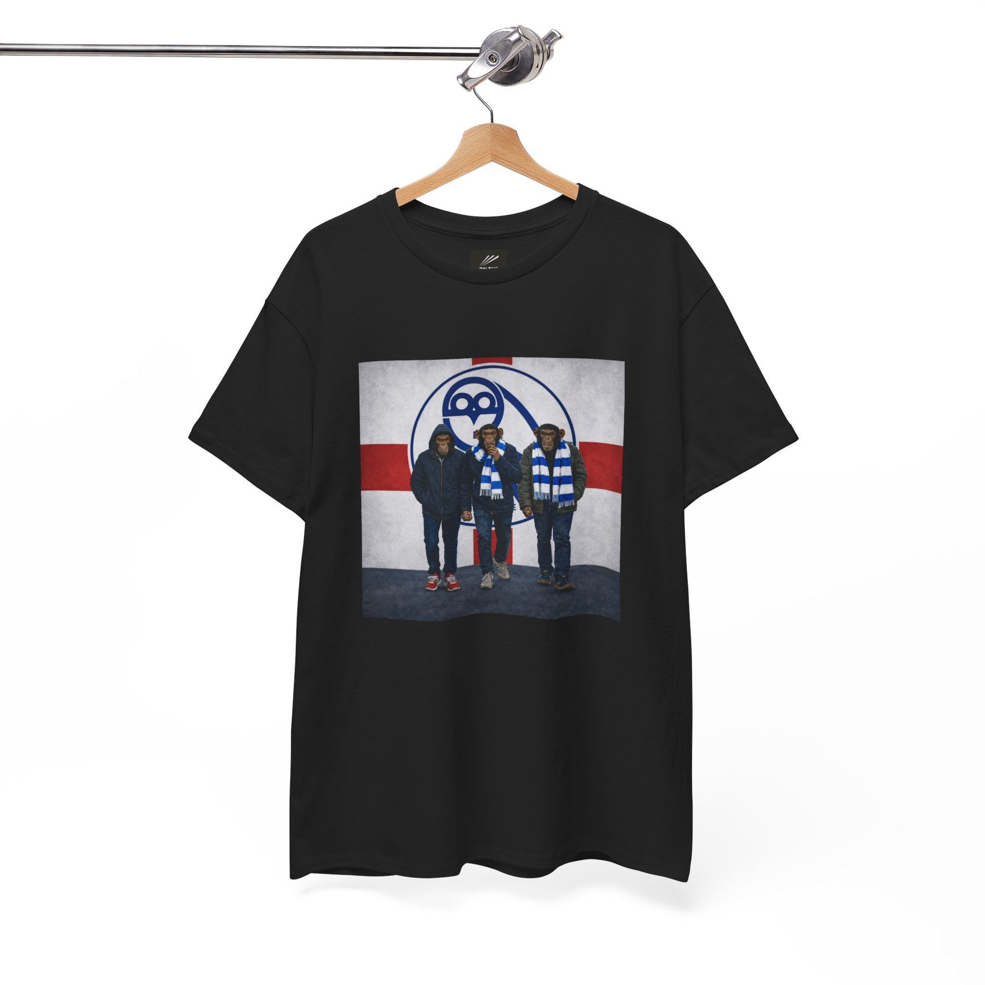 A black short-sleeve swfc t-shirt hanging on a wooden hanger from a metal rack, featuring a graphic print of the band Death Cab for Cutlass on a white, red, and blue background.