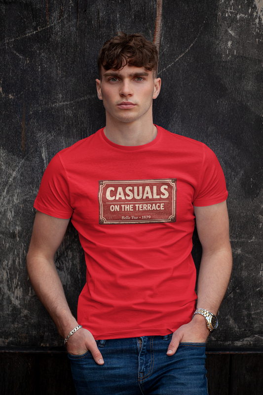 A man wearing a red DRFC t-shirt flat lay featuring a central vintage red and white street sign graphic reading "CASUALS ON THE TERRACE" with "Belle Vue • 1879" printed below, and an inner neck label for On The Terrace., posed against a dark textured wall.