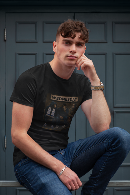 A man wearing a black graphic swfc t-shirt with a 'Wednesday' print, paired with blue jeans, posing in front of a dark paneled door.
