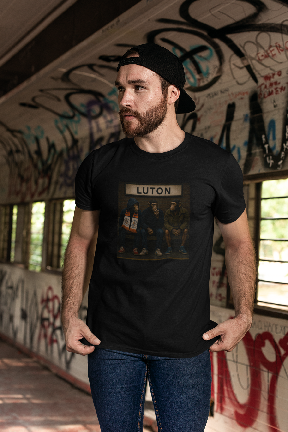 Man wearing black Luton Town Terrace Monkeys T-shirt in a graffiti tunnel