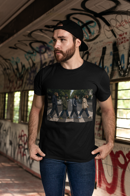 Man wearing black Beatles Abbey Road Casuals T-shirt by a graffiti wall