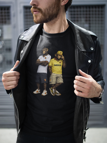 A man wearing a black leather jacket over a black Watford t-shirt featuring a print of two football players with 'IVECO' branding, posed against a gray metal shutter background.