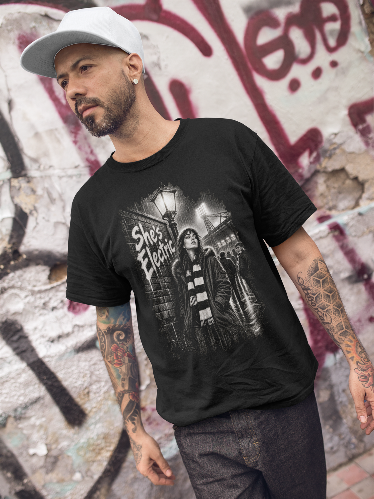 Tattooed man walking past graffiti in black Oasis She's Electric T-shirt